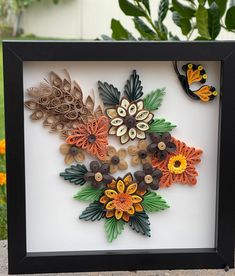 there is a shadow box with some flowers in it and two butterflies on the side