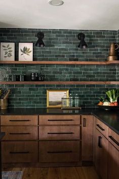 a kitchen with wooden cabinets and black counter tops in front of green brick wall tiles