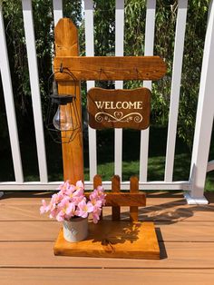 a welcome sign sitting on top of a wooden bench next to a potted plant