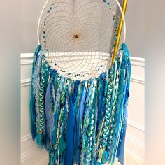 a blue and white dream catcher hanging on the wall next to a gold stick in it