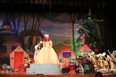 an image of a stage scene with people dressed in costumes and props on the stage