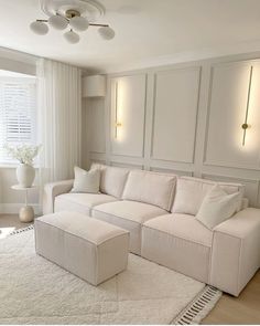 a living room with a white couch and ottoman on the floor in front of a window