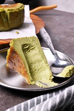 a piece of green cake on a plate with a fork and knife next to it