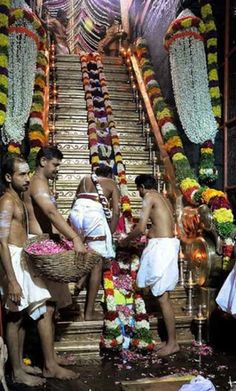 men in white robes are standing on the steps with flowers and garlands around them