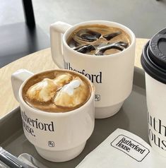 two cups of coffee on a tray with spoons