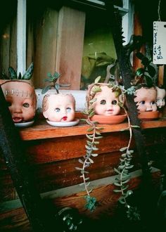 five ceramic heads are sitting on a window sill