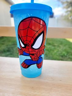 a plastic cup with a spiderman design on it sitting on a table outside in the sun