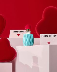 a red and white box with a blue bottle on it next to two heart shaped boxes