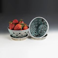 two bowls filled with strawberries on top of each other