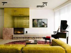 a living room filled with furniture and a piano in front of a fire place next to a window