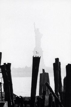 the statue of liberty is silhouetted against an overcast sky in black and white