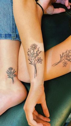 two women with matching tattoos on their legs sitting next to each other and holding hands