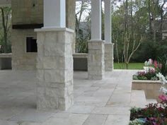 an outdoor patio with stone pillars and flowers