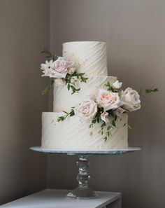 two tiered white wedding cake with flowers on top