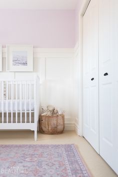 a baby's room with a crib, rug and pictures on the wall