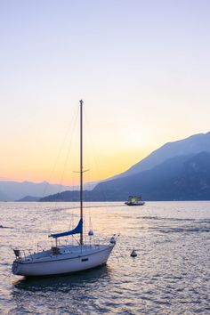 a sailboat floating in the water at sunset