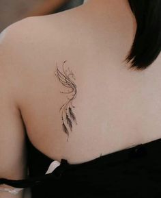 the back of a woman's shoulder with a feather tattoo on her left side