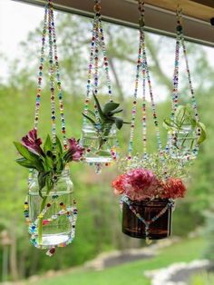 three hanging vases filled with flowers on a window sill