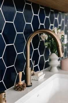 a bathroom sink with a gold faucet and blue tiled wall in the background