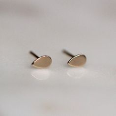 - Handcrafted out of 14K yellow gold - Drop measures 5.5 by 3.2mm - Comes with butterfly push backings  - Available in a shiny or matte finish - select in the drop down menu if you would like a single stud or a pair. The video shows the shiny on top and matte on the bottom. For the earrings pictured in the second hole click here: https://www.etsy.com/listing/180321792/solid-10k-gold-line-studs-square-bar?ref=shop_home_feat_m Processing Times -  Current processing time is a few days.  Each Item i Studs Gold Earrings, Square Bar, Studs Gold, Minimal Earrings, Dainty Studs, Minimal Jewelry, Gold Dots, Circle Studs