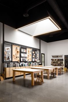 an empty room with tables and stools in the center, surrounded by bookshelves