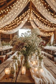 mason jars filled with flowers and lit candles on a wooden table