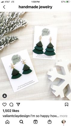 two christmas tree earrings on top of a table