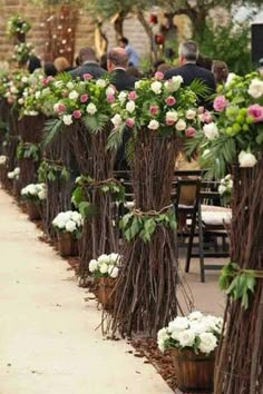 an outdoor ceremony with white and pink flowers in vases on the side of the aisle