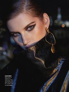 a woman with black and gold makeup is posing for a magazine cover shot in front of a cityscape