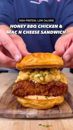 a person is holding up a chicken and mac n cheese sandwich on a cutting board