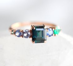 Unique Cluster ring made with gorgeous teal emerald cut sapphire and side sapphires/emerald. A beautiful modern ring for her. ★Details Center stone: 1.7ct natural teal sapphire Setting: four prong Accent stones sapphires, emerald Band width: approx. 1.6 mm Material: 14k/18k yellow/white/rose gold or platinum for an additional fee Size: 3-8 (Larger and smaller sizes are available as well. Priced upon request.) ★Procedure information Please select the style and ring size from the drop-down menu on Emerald Cut Multi-stone Sapphire Ring, Sapphire Cluster Ring, Statement Engagement Ring, Emerald Band, Matching Wedding Rings, Teal Sapphire, Cluster Engagement Ring, 14k Rose Gold Ring, Modern Ring