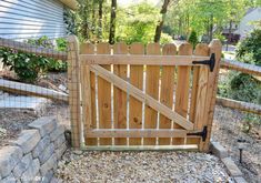 a wooden gate is open on the side of a house in front of a stone wall