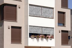 two windows with brown shutters on the side of a white and beige building,