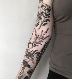 a woman's arm with flowers and mushrooms tattooed on the left side of her arm