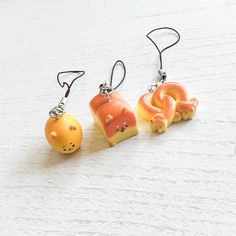 three small items are hanging from hooks on a white surface, one is orange and the other is yellow