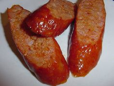 three sausages on a white plate with ketchup