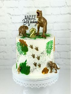 a birthday cake decorated with dinosaurs and leaves