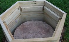 a wooden box sitting in the middle of some grass and rocks on top of it