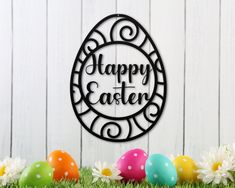 a metal sign that says happy easter next to eggs in the grass with daisies