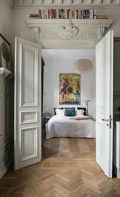 an open door leading to a bedroom with a bed and bookshelf on the ceiling