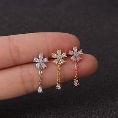 a person is holding three different types of earrings in their hand and one has a cross on it