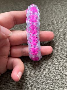 a hand holding a pink and purple ring