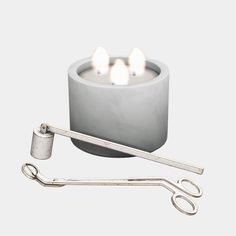 a candle with three candles on it and a pair of tongs next to it