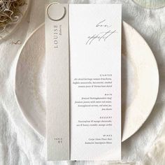 a place setting with a white plate and silverware on it, along with a menu card