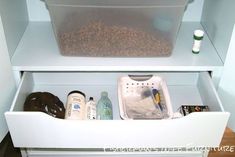 an open refrigerator with food and condiments in the bottom drawer, on top of a wooden floor