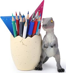 a toy dinosaur holding a pencil holder with colored pencils in it