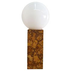 a white ball sitting on top of a wooden block next to a glass ball in the middle