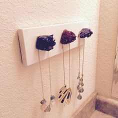 five necklaces hanging on the wall in a bathroom