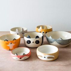 five bowls with different designs on them sitting on a table next to each other and one has an animal face painted on it