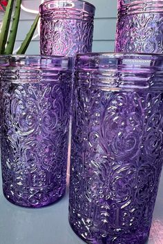 four purple glass jars sitting on top of a table